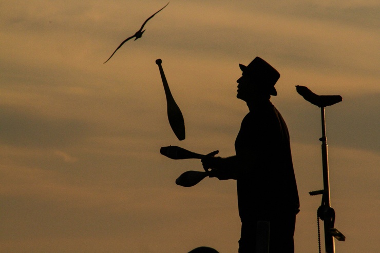 Silhouette of a Juggling Street Performer and His Unicycle at Sunset